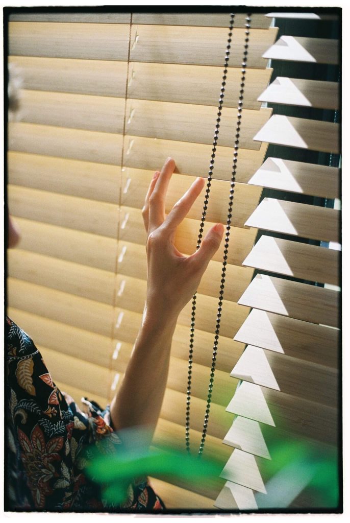 woman looking through blinds